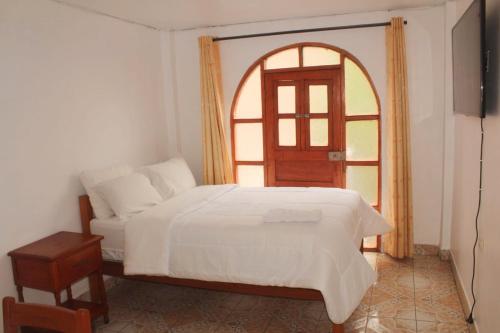 a bedroom with a white bed and an arched window at MESONERO in Ayacucho