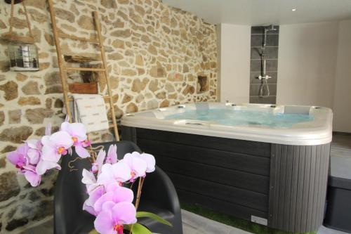 baño con bañera y flores púrpuras en La Maison Vieille avec Spa Privé, en Savas