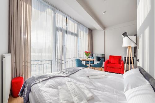 a bedroom with a large bed and a red chair at Apartamenty Sun & Snow Resorts A Białka Tatrzańska z sauną in Białka Tatrzańska