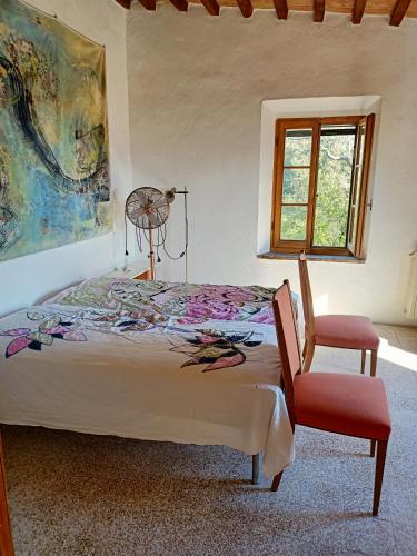a bedroom with a bed and a window and a chair at Il Casolare del Pastore in Suvereto