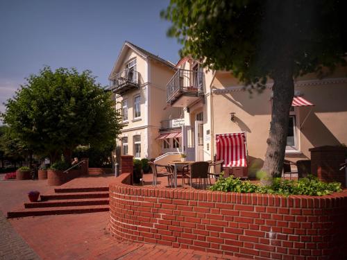 a brick wall with a table and chairs in front of a building at Hotel Hüttmann in Norddorf