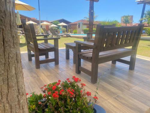 two wooden benches and a table and flowers on a patio at Pousada Mirante das Estancias in Águas de Lindóia