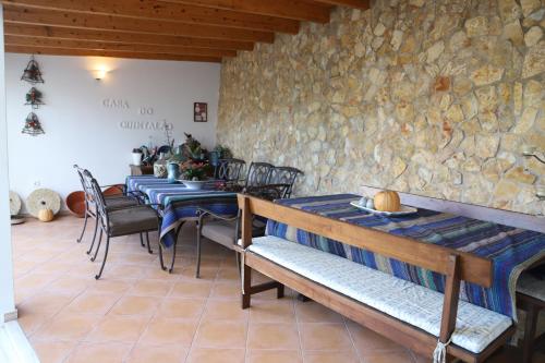 a dining room with tables and chairs and a stone wall at Casa do Quintalão in Raposeira