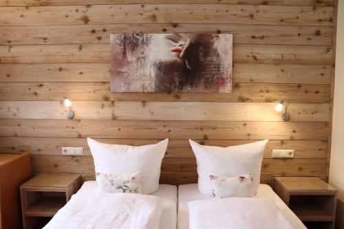 two beds in a room with a wooden wall at Haus Hubertus in Bad Peterstal-Griesbach