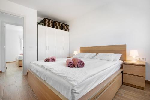 ein Schlafzimmer mit einem großen weißen Bett mit rosa Handtüchern darauf in der Unterkunft Casa Aliana in Puerto del Rosario