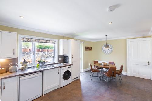 a kitchen and dining room with a sink and a table at Cannich Cottage at Parbroath Farm in Cupar