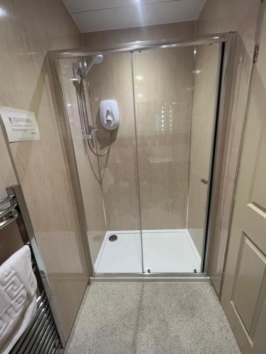 a shower with a glass door in a bathroom at Links Lets Room Only in Seahouses