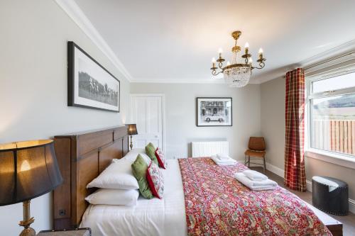 a bedroom with a bed and a chandelier at Cannich Cottage at Parbroath Farm in Cupar