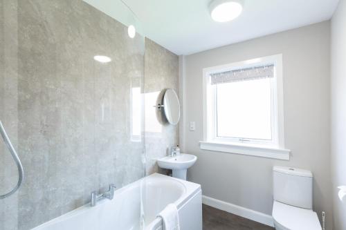 a bathroom with a tub and a toilet and a sink at Cannich Cottage at Parbroath Farm in Cupar