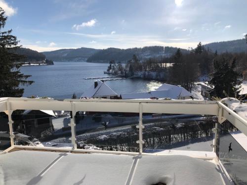 a view of a lake from a balcony with snow at Sunside Ferien Wellness Oase Hotel Apartment's Schwarzwald am Schluchsee in Schluchsee