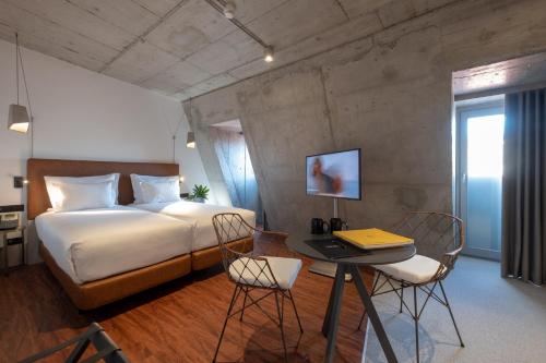 a bedroom with a bed and a desk with a laptop at Hotel Cajú in Funchal