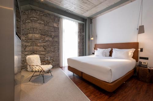 a bedroom with a large bed and a stone wall at Hotel Cajú in Funchal