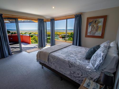 a bedroom with a bed and a balcony at Aorere House - Collingwood Holiday Home in Collingwood