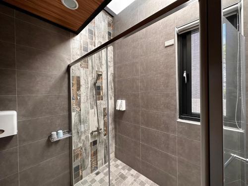 W łazience znajduje się prysznic ze szklanymi drzwiami. w obiekcie Hermes B&B w mieście Neipu