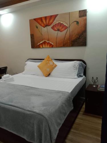 a bedroom with a bed with a painting on the wall at Point Gate Inn in Bacolod