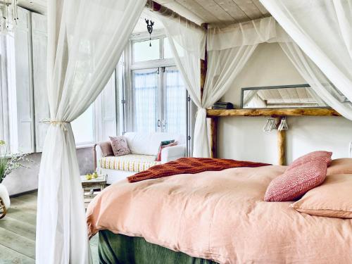 a bedroom with a canopy bed and a chair at In de Aap - Appartementen & Guesthouse in Bergen