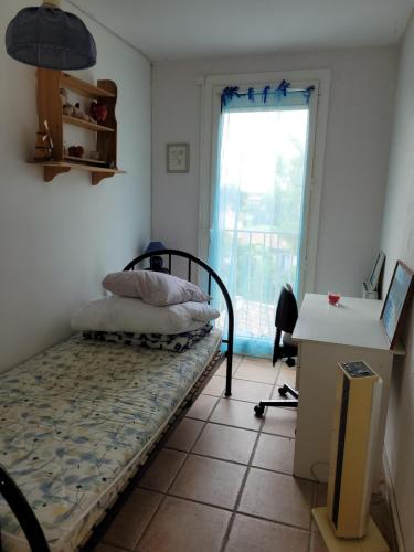 1 dormitorio con cama, escritorio y ventana en Appartement 7 couchages en Salon-de-Provence