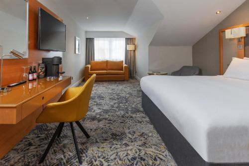 a hotel room with a large bed and a desk at Chesford Grange Hotel in Kenilworth