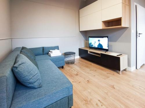 uma sala de estar com um sofá azul e uma televisão em Stara Drukarnia - Apartamenty typu Studio em Bydgoszcz