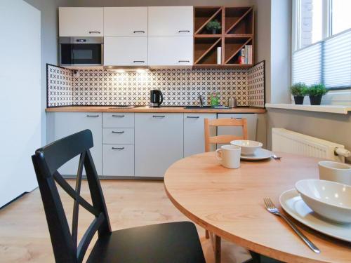 a kitchen with a wooden table and a dining room at Stara Drukarnia - Apartamenty typu Studio in Bydgoszcz