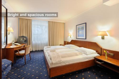ミュンヘンにあるアンバサダー パークホテルのベッドとデスクが備わるホテルルームです。