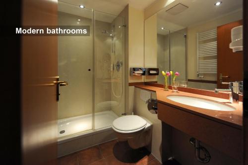 a bathroom with a toilet and a shower and a sink at Ambassador Parkhotel in Munich