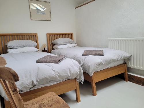 two twin beds in a room with white walls at The Long Barn in Skibbereen