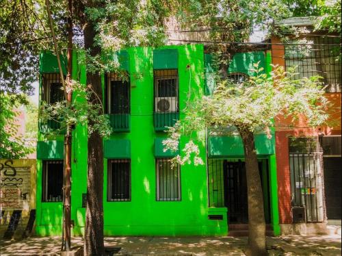 um edifício verde com árvores em frente em Clover Hostel em Mendoza