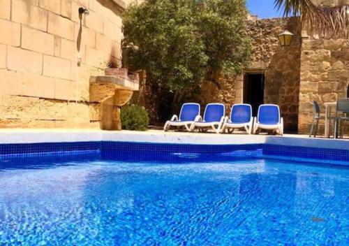 a group of blue chairs sitting next to a swimming pool at Villa Ta Marija in Xagħra