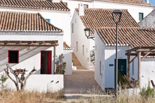une rue dans un village avec des maisons blanches dans l'établissement Aldeia da Pedralva - Slow Village, à Vila do Bispo
