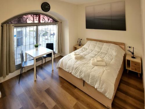 a bedroom with a bed and a table and a window at Jaffa 17 - Lihi brand new studio in Jerusalem