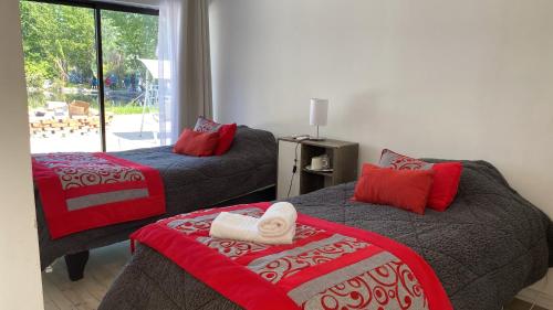 Hostal Doñihue في Doñihue: غرفة نوم بسريرين حمراء ورمادية