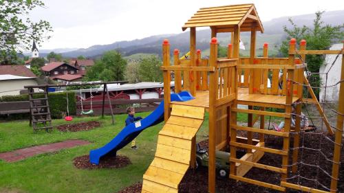 un niño jugando en un parque infantil con un tobogán en Leihwohnwagen Camping-Aach, en Oberstaufen