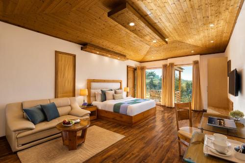 a bedroom with a bed and a couch in a room at Baragarh Resort & Spa, Manali- IHCL SeleQtions in Manāli