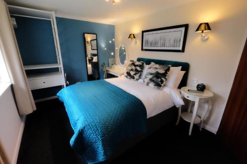 a bedroom with a blue and white bed and a table at Distant Hills Guest House in Spean Bridge