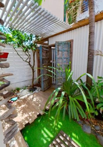 einen Garten mit einer Terrasse mit einem Zaun und einer Pflanze in der Unterkunft Calme et apaisant in La Saline-Les-Bains