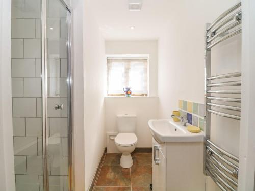 a white bathroom with a toilet and a sink at Bailey Cottage in Truro
