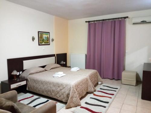 1 dormitorio con cama y cortinas moradas en Hotel Panorama en Agios Panteleimon