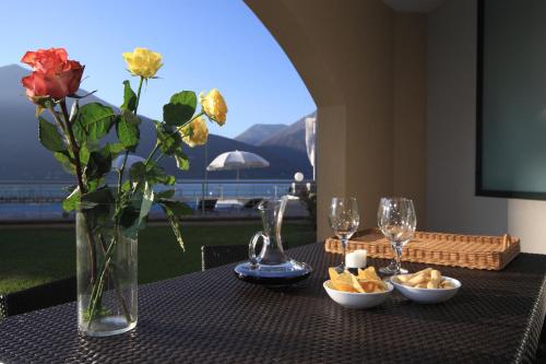 a table with a vase of flowers and a table with a view at Golfo Gabella Lake Resort in Maccagno Superiore