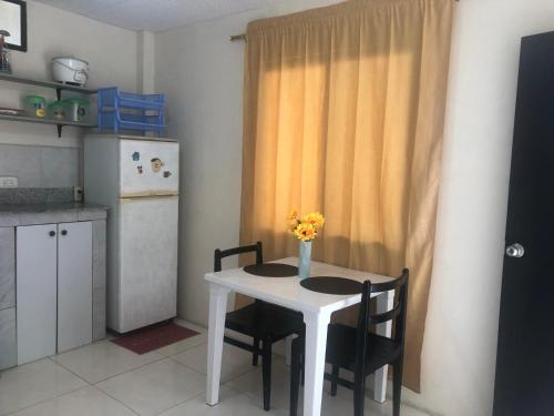 una pequeña cocina con mesa blanca y sillas en Hospedaje Maluli suit 4, en Santa Elena