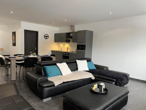 a living room with a black couch and a table at Loft à la Source in Francorchamps