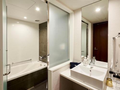 uma casa de banho com um lavatório, uma banheira e um chuveiro em Daiwa Roynet Hotel Kumamoto Ginzadori PREMIER - former Daiwa Roynet Hotel Kumamoto Ginzadori em Kumamoto