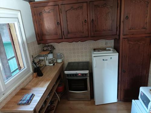a kitchen with wooden cabinets and a white refrigerator at Joli 3 pièces au calme in Saint-Martin-Vésubie