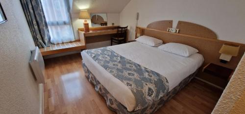 a hotel room with a bed and a desk at Kyriad Direct Arpajon in Arpajon