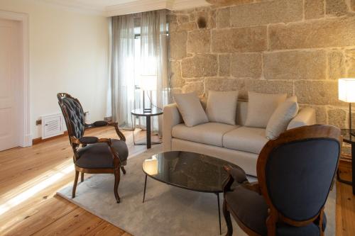 sala de estar con sofá y pared de piedra en Pazo Torre Penelas en Portas