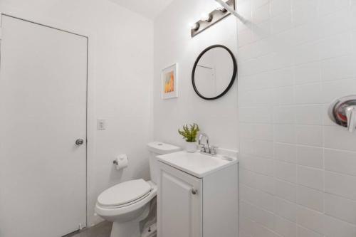een witte badkamer met een toilet en een spiegel bij Fabulous Studio 15 min from The Beach in Miami