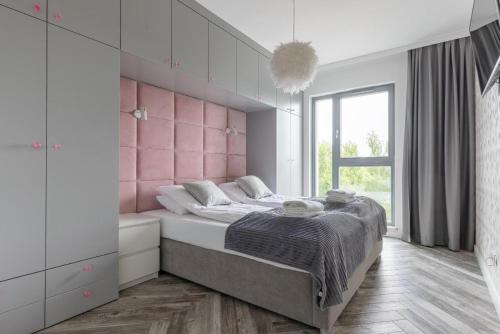 a bedroom with a large bed with a pink headboard at Nadmorze by Q4Apartments in Gdańsk
