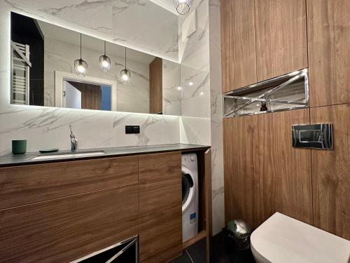 a bathroom with a sink and a washing machine at Nadmorze by Q4Apartments in Gdańsk