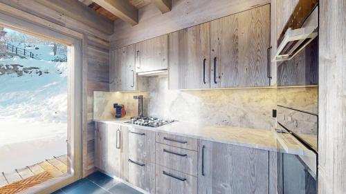 una cocina con armarios de madera y una gran ventana en Ecureuil noir COSY & QUIET chalet 10 personnes en Vex