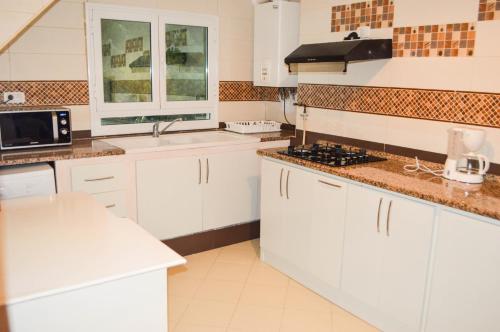 Cosy S3 Apartment in Sidi Bou Said Village في سيدي بو سعيد: مطبخ مع دواليب بيضاء ومغسلة